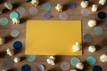 yellow surface with copy space, overflowing popcorn, colorful confetti around it