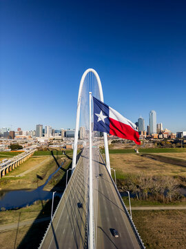 Texas state flag and Modern Margaret Hunt Hill Bridge over Trinity river in Dallas, Texas on a sunny day.