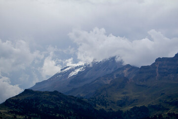 Obraz premium Panoramic alpine ridge under rolling clouds with snow patches. Empty sky for headlines – perfect for 4K wallpapers, eco blogs, travel promos.