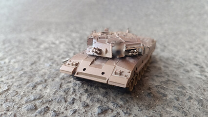 Realistic miniature military tank model with rocket launcher on a textured concrete surface,...
