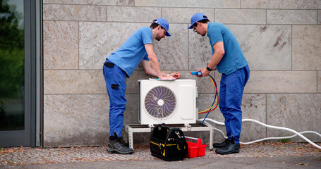 Hispanic Male HVAC Technician Inspecting Commercial Air Conditioning Unit