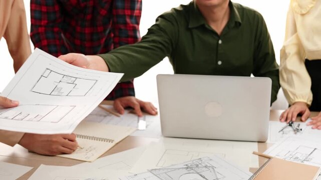 Smart architect and safety engineer discussion about building plan on table with architectural document, measurement tools and wooden block scatter around at modern office. Closeup. Delineation.