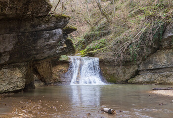 spring in nature, a shallow riverbed with a small flow of water in a wooded area
