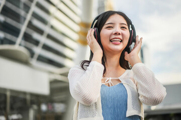 Young asian woman wearing headphones and enjoying music on the urban city, Female listening to...