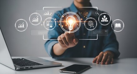 A person interacting with a digital interface with icons and a lightbulb on a desk with devices