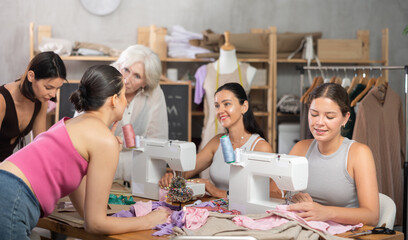 Group of happy attendees of dressmaking courses sewing, drawing with curves and communicating