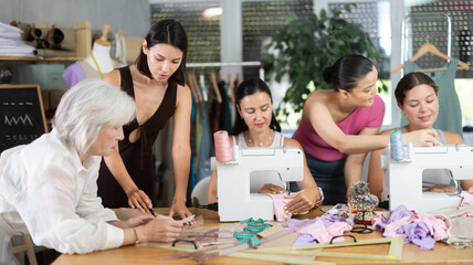 Adult woman teacher shows group women how to draw pattern on paper at sewing master class