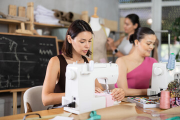 Positive young and middle-aged women working with sewing machine at dressmaking classes