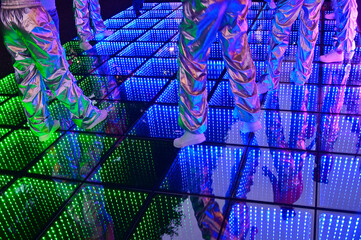 Unrecognizable group of people dancing on colorful LED lights dance floor