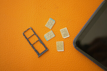 SIM card tray and multiple SIM cards on an orange surface
