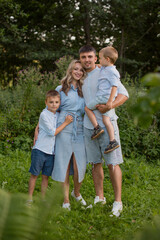 Fototapeta premium A happy man and a woman with two children. Raising a son. Spending time outdoors with family.