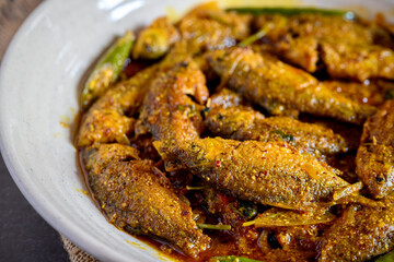 Bengali-style puti fish jhal served in a bowl – spicy small fish curry, traditional Bengali non-veg dish, puti macher jhal, Indian freshwater fish in mustard gravy, homestyle overhead view

