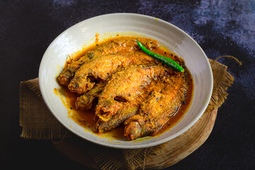 Bengali-style pabda fish in tomato-based red curry – pabda macher jhol, traditional Bengali fish dish, Indian freshwater fish curry, spicy homestyle fish preparation, overhead view

