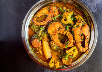 Traditional Bengali-style rohu fish curry with seasonal vegetables served in a steel serverware – everyday Indian fish curry, homestyle rui macher jhol, rustic Bengali lunch, overhead view