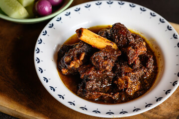 Traditional Bengali-style mutton kosha served in a small white bowl – spicy Indian goat curry, authentic Bengali kosha mangsho, slow-cooked meat dish, homestyle mutton curry, rustic overhead view