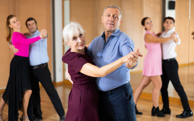 active elderly people attend dance lessons for amateurs and learn to dance waltz in their free time