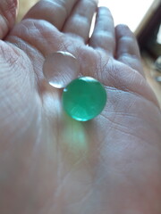 Hand holding two transparent balls, white and green