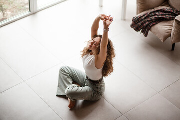 Young woman listen musik in headphones and dansces at home in the morning. The woman dressed jeans and plaid shirt