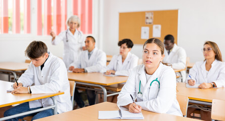 Focused young girl medical intern listening to lecture at university for professional development...