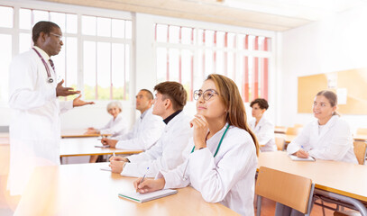 Portrait of focused young hispanic woman doctor listening lectures within refresher course....