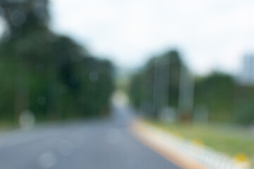 Blurred view of highway road with natural surroundings, green trees and blue sky, creating a dreamy travel and journey mood.