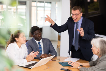 Group of business people discussing negative issues while sitting at table in office