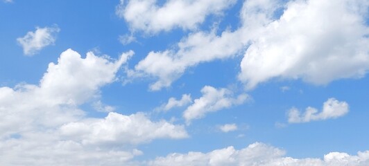 Fototapeta premium Panoramic cloudscape in clear blue sky in summer. Nature sky background with fluffy clouds.
