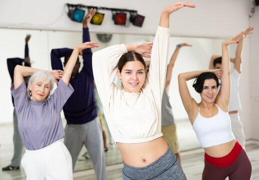Smiling attractive young girl enjoying latin dances in modern studio, practicing passionate bachata during group class