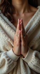 Woman in a white sweater is holding her hands together meditation