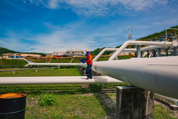 Male worker inspection at steel long pipes and pipe elbow in station oil factory during refinery...