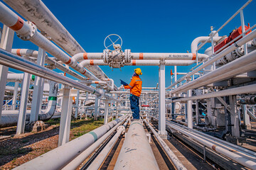 Male worker inspection at steel long pipes and pipe elbow in station oil factory during refinery...