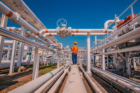 Male worker inspection at steel long pipes and pipe elbow in station oil factory during refinery valve of visual check record