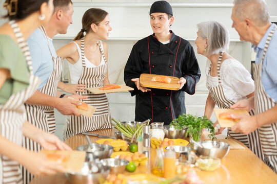 Professional personal chef cook in customer private kitchen house giving a cooking lesson to people at home - Powered by Adobe