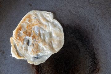 Roti being fried in a cast iron pan, a street food in southern Thailand.
