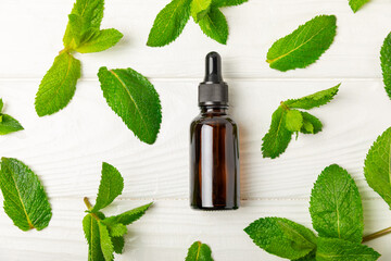 Essential oil mint on a wooden background. Peppermint essential oil with fresh mint leaves. A...