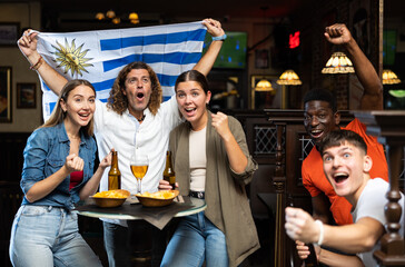 Fans with the flag of Uruguay celebrate the victory of their favorite team in a beer bar