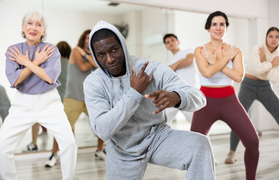 African-american guy doing hip-hop dance moves with other people in dance studio