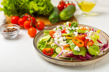 Cucumber salad on a wooden background.Homemade salad with fresh vegetables, cucumber, tomato, sweet pepper and lettuce in a plate.Vegetarian spring salad.Vegetarian diet.Healthy eating.Space for text