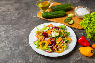 Cucumber salad on a wooden background.Homemade salad with fresh vegetables, cucumber, tomato, sweet pepper and lettuce in a plate.Vegetarian spring salad.Vegetarian diet.Healthy eating.Space for text