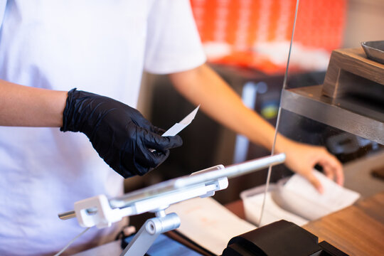 Cashier staff using tablet to receive orders from customers at counter service in cafe or store. Cashier takes payment from customer with tablet.