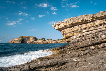 Scenic rocky coastline with calm sea and forest background at Sardala Bay Kocaeli - peaceful beach landscape on sunny day with dramatic rock formations