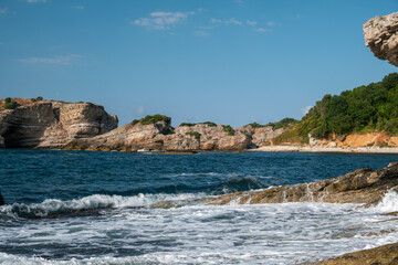 Scenic rocky coastline with calm sea and forest background at Sardala Bay Kocaeli - peaceful beach landscape on sunny day with dramatic rock formations