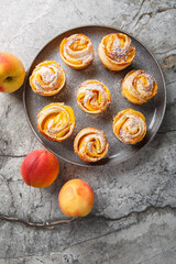 Peach Puff Pastry Roses are the perfect easy dessert  closeup on the plate on the table. Vertical top view from above