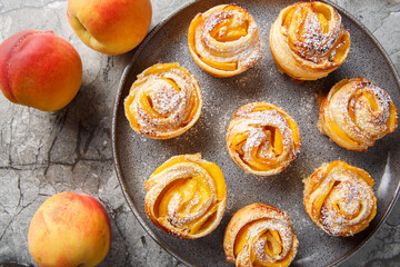 puff pastry peach roses mini tarts muffins close-up on a plate on a table. horizontal top view from above