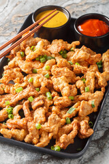 Chinese fast food crispy small pork xiaosurou with sauces close-up on plate on table. Vertical