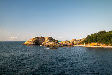 Scenic rocky coastline with calm sea and forest background at Sardala Bay Kocaeli - peaceful beach landscape on sunny day with dramatic rock formations