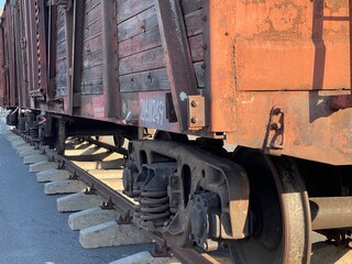 A weathered, rustic wooden freight train car on tracks under a clear sky, showcasing industrial...