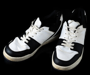 Used black and white low top sneakers with laces vintage sports shoes black background