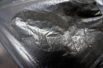 Wrinkled dark plastic bag used for recycling close up shot for background.