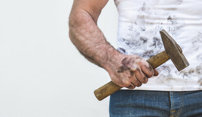 Handsome worker, hammer and dirty t-shirt. Labor day. Front view, close up, studio shot. Labor and employment concept